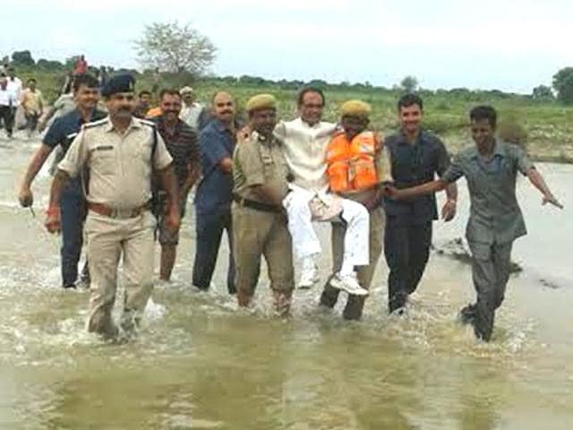 Chief minister Shivraj Singh Chouhan visited flood affected Samtana village in Panna district on Sunday. In a flooded area of the district, Chouhan was carried by security personnel above the water level.(Hindustan Times)