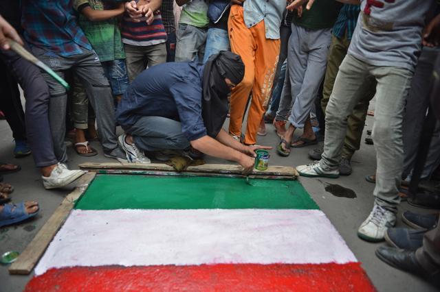 A masked Kashmiri protestor paints a graffiti representing the Indian flag on a road during a protest in downtown Srinagar. (AFP) A masked Kashmiri protestor paints a graffiti representing the Indian flag on a road during a protest in downtown Srinagar. (AFP)