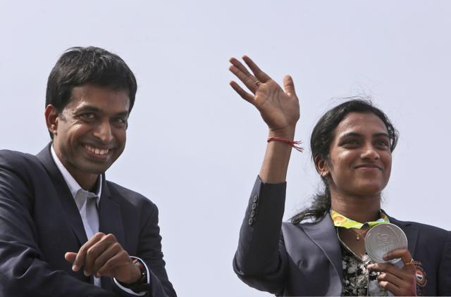 Pusarla Sindhu, right, displays her silver medal as she is brought home in a procession along with her coach, Pullela Gopichand, upon their arrival in Hyderabad. (AP)