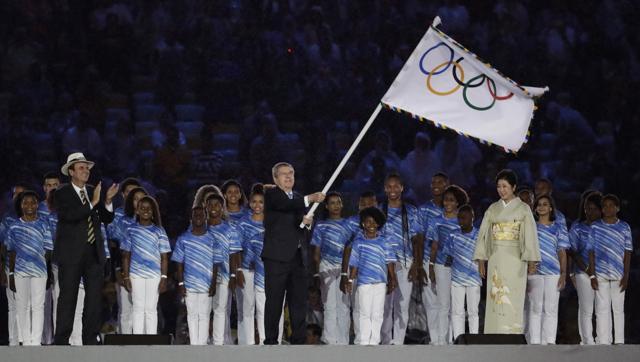 IOC President Thomas Bach, centre, waves the Olympic flag. (AP)