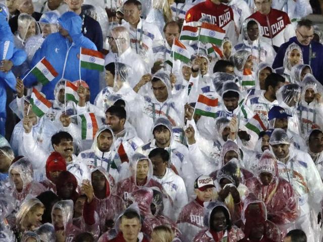 Athletes from India march into the closing ceremony holding flags and wearing raincoats to protect themselves. (AP)