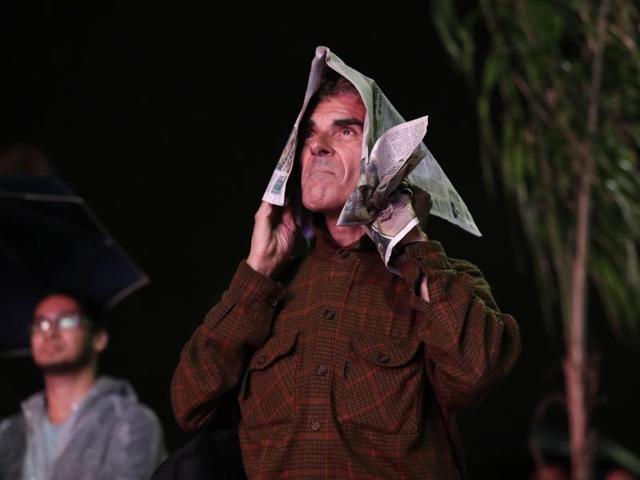 A man covers himself with a newspaper to protect himself from the rain as he watches the closing ceremony on an outdoor display in Rio de Janeiro. (AP)