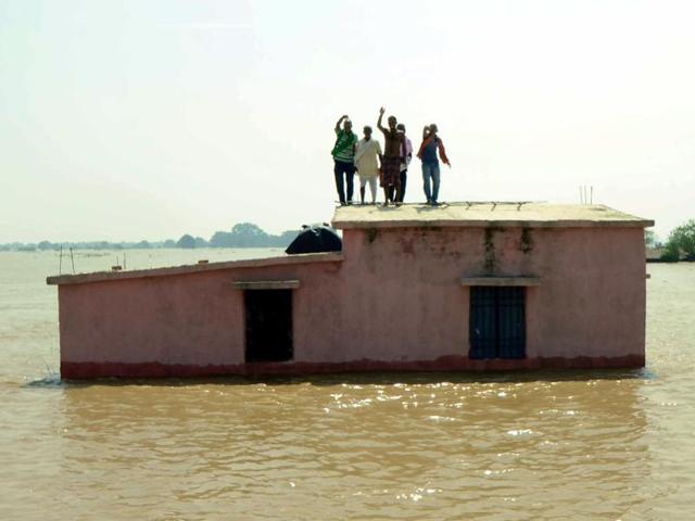 People stand on the roof of a submerged house as they wait to be rescued at Kasimpurchak, near Danapur Diara in Patna, Bihar.(AFP Photo)