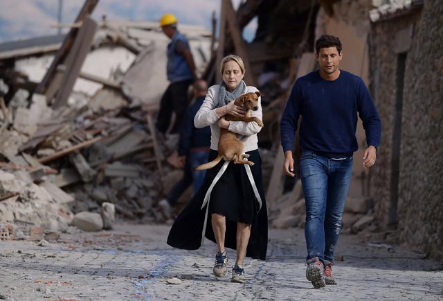 A woman holds a dog in her arms as she walks with a man next to the rubble of buildings in Amatrice. (AFP Photo) A woman holds a dog in her arms as she walks with a man next to the rubble of buildings in Amatrice. (AFP Photo)