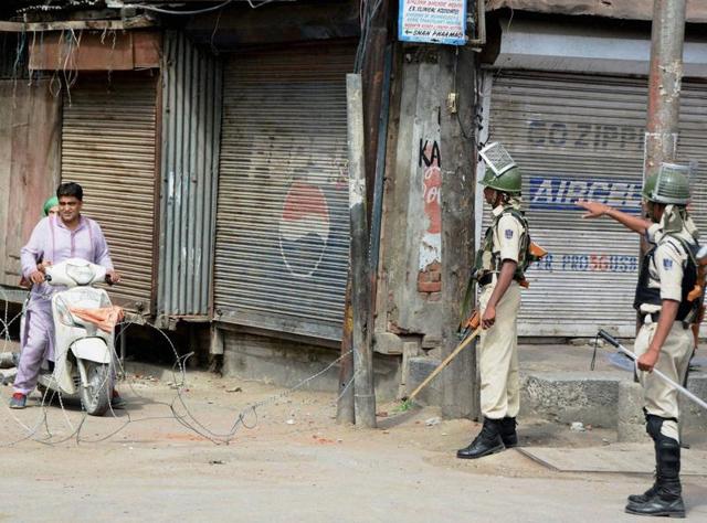 Security jawans stop a motorbiker during curfew and strike in Srinagar. (PTI Photo) Security jawans stop a motorbiker during curfew and strike in Srinagar. (PTI Photo)