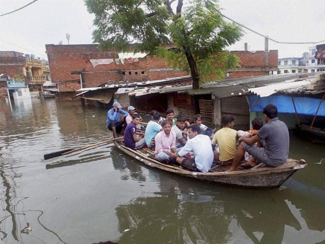 People on boat, wade through the flooded streets in Allahabad on Tuesday.  (PTI) 
