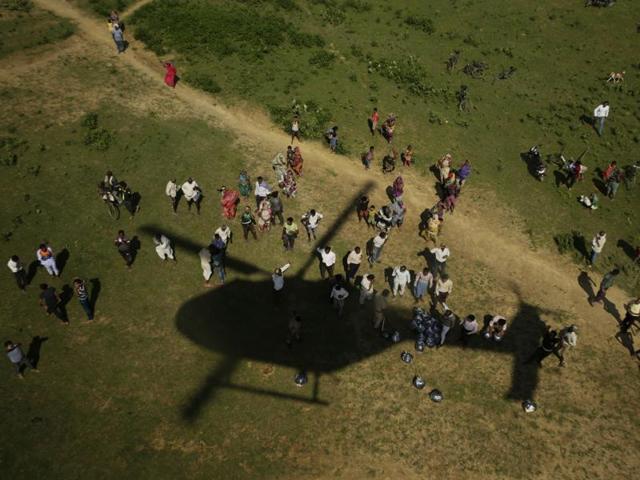 People wait for relief supplies being distributed by helicopter, near Allahabad on August 24. Heavy rains in many parts of northern India have lead to Ganges and Yamuna flooding villages and cities. (AP/Rajesh Kumar Singh) 