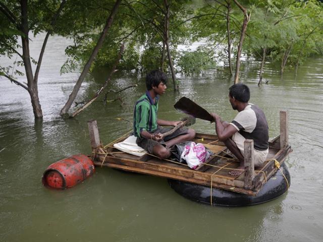 Two men carry essentials like a gas cylinder to their temporary shelter by a makeshift raft after several areas were flooded in Allahabad. Heavy rainfall in the upper reaches of the country has caused rivers to overflow endangering lives and properties of people along the river Ganges as also in other parts of the country.  (AP Photo/ Rajesh Kumar Singh) 