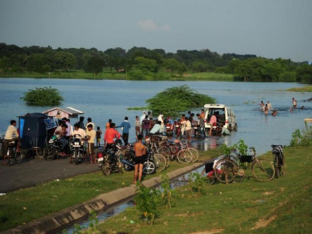 Villagers gather to wash their vehicles on a section of the partially flooded National Highway between Varanasi and Kanpur at Kurehar near Allahabad.  (AFP/Sanjay Kanojia) 
