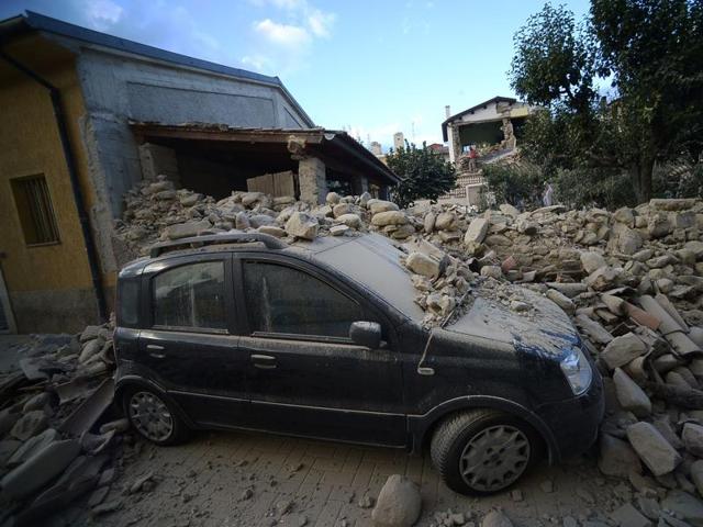 A car lies under a damaged wall after a strong earthquake hit Amatrice, a mountain village in neighbouring Lazio that was packed with visitors at the peak of the summer season. “Half the village has disappeared,” said Sergio Pirozzi, Amatrice’s mayor. (AFP Photo)