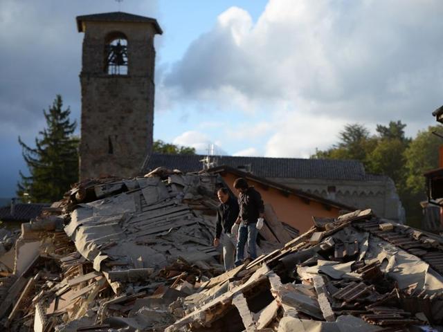 Two men walk on a damaged home after a strong earthquake hit Amatrice. The first quake struck shortly after 3.30 am (0130 GMT), according to the United States Geological Survey. (AFP Photo)