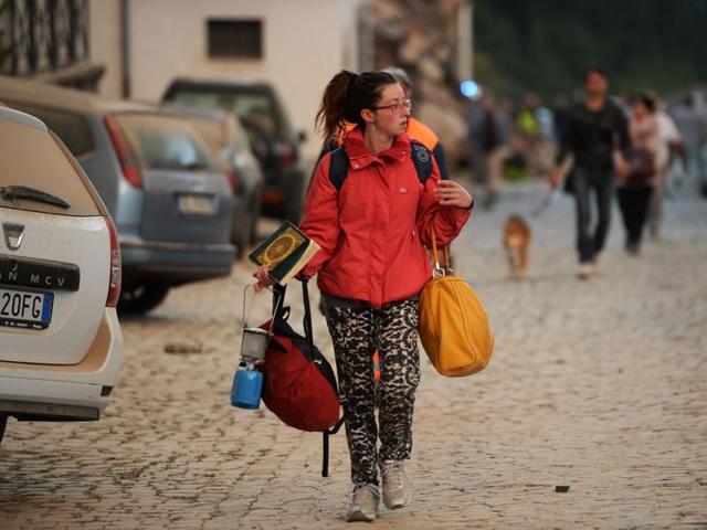 Residents look at damaged buildings after a strong earthquake hit Amatrice. (AFP Photo)