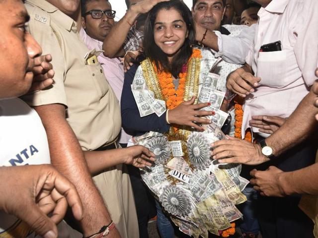 Sakshi Malik is welcome with a garland of flowers and currency notes on her arrival at Tikri Border village on her way to her home town at Rohtak. (Vipin Kumar/HT PHOTO) Sakshi Malik is welcome with a garland of flowers and currency notes on her arrival at Tikri Border village on her way to her home town at Rohtak. (Vipin Kumar/HT PHOTO)