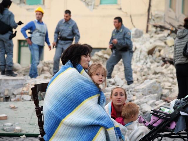 Victims sit among the rubble of a house after a strong earthquake hit Amatrice on August 24, 2016. (AFP Photo)