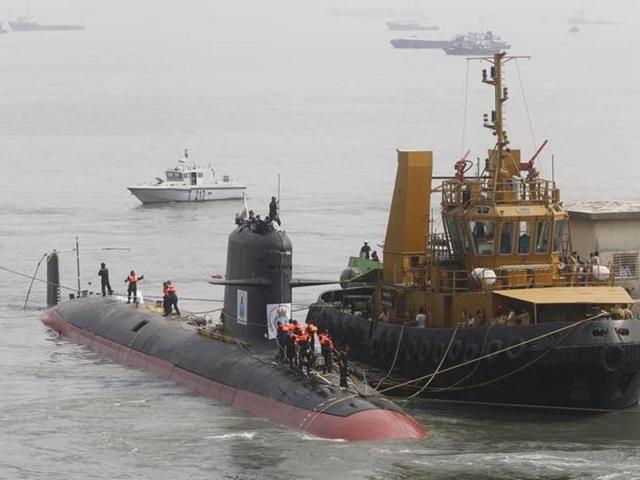Employees stand in front of the Indian Navy's first Scorpene submarine before being undocked from Mazagon Docks Ltd, in Mumbai.(Reuters File Photo)