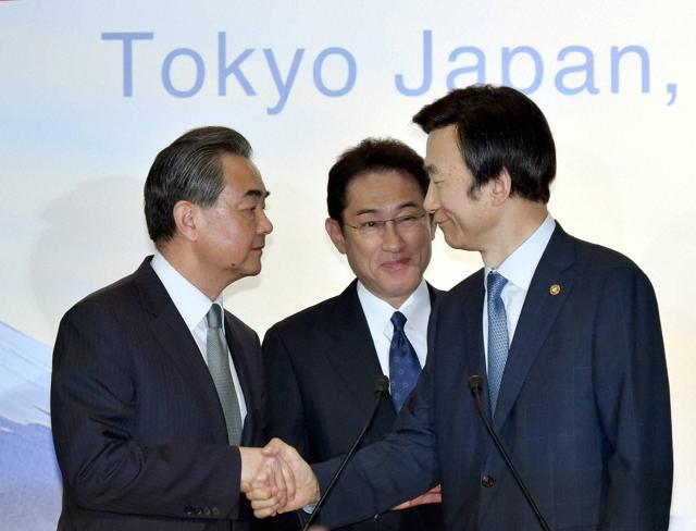 Japanese foreign minister Fumio Kishida, (centre), watches as his Chinese counterpart Wang Yi, (left), shakes hands with South Korean foreign minister Yun Byung-se after the news conference following the trilateral meeting in Tokyo on Wednesday. The foreign ministers criticised North Korea's latest submarine missile test during their annual talks held amid lingering frictions over territorial disputes and wartime history. (AP) Japanese foreign minister Fumio Kishida, (centre), watches as his Chinese counterpart Wang Yi, (left), shakes hands with South Korean foreign minister Yun Byung-se after the news conference following the trilateral meeting in Tokyo on Wednesday. The foreign ministers criticised North Korea's latest submarine missile test during their annual talks held amid lingering frictions over territorial disputes and wartime history. (AP)