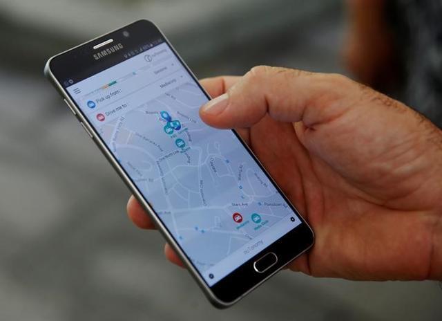 A staff member of nuTonomy demonstrates their self-driving taxi booking app on a mobile phone drives during its public trial in Singapore on Wednesday. (Reuters) A staff member of nuTonomy demonstrates their self-driving taxi booking app on a mobile phone drives during its public trial in Singapore on Wednesday. (Reuters)
