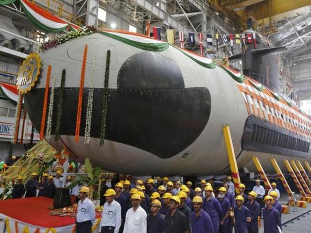 Employees stand in front of the Indian Navy's first Scorpene submarine before being undocked from Mazagon Docks Ltd, a naval vessel ship-building yard, in Mumbai.(Reuters file)