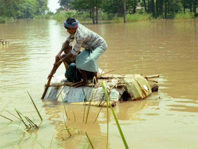 A man tries to cross a flooded area using a hand-made raft in Vaishali district. (PTI) A man tries to cross a flooded area using a hand-made raft in Vaishali district. (PTI)