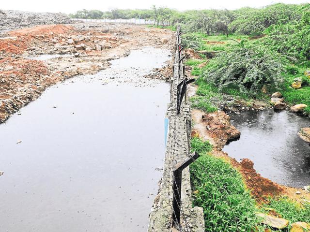 Contaminated water leaks from Bandhwari plant (on left) and collects outside the compound wall on forest land. (HT File) Contaminated water leaks from Bandhwari plant (on left) and collects outside the compound wall on forest land. (HT File)