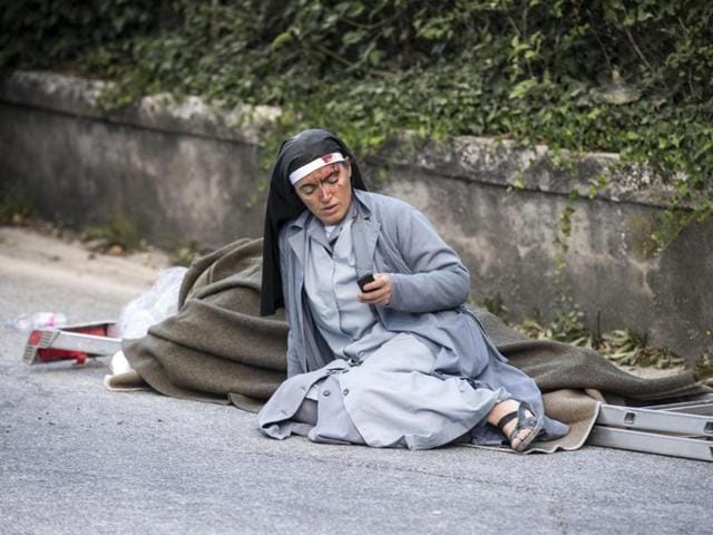 Sister Marjana Lleshi checks her mobile phone as she lies near a ladder following an earthquake in Amatrice. (AP) Sister Marjana Lleshi checks her mobile phone as she lies near a ladder following an earthquake in Amatrice. (AP)