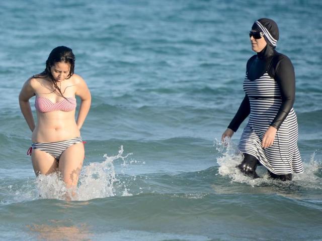 This file photo shows Tunisian women, one (right) wearing a ‘burkini’, a full-body swimsuit designed for Muslim women, swimming at Ghar El Melh beach near Bizerte, northeast of the capital Tunis. The ban on the Islamic burkini swimsuit on some French beaches has triggered disdain in English-speaking countries, where outlawing religion-oriented clothing is seen as hampering integration.(AFP Photo)