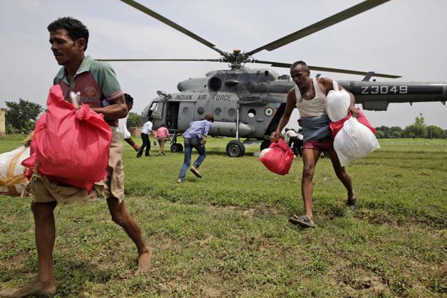 Flood affected people take relief material flown in by the Indian Air Force helicopter on the outskirts of Allahabad on Friday (AP) Flood affected people take relief material flown in by the Indian Air Force helicopter on the outskirts of Allahabad on Friday (AP)
