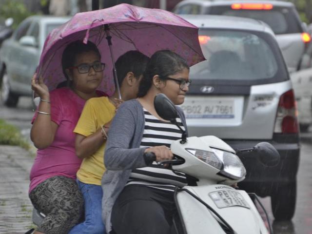 Youngsters near Golden Temple, Amritsar, in the rain on Saturday . (Sameer Sehgal/HT Photo)