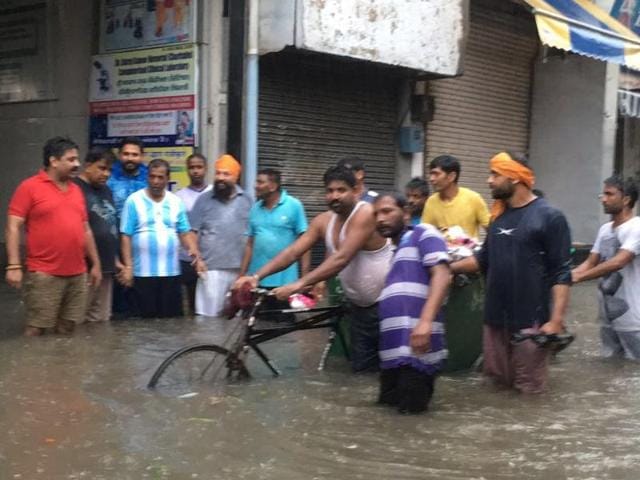 Phagwara MLA Som Parkash (fourth from left) and mayor Arun Kholsa (to his right) with local BJP workers standing in knee-deep water during rain in Phagwara on Saturday.(HT Photo)