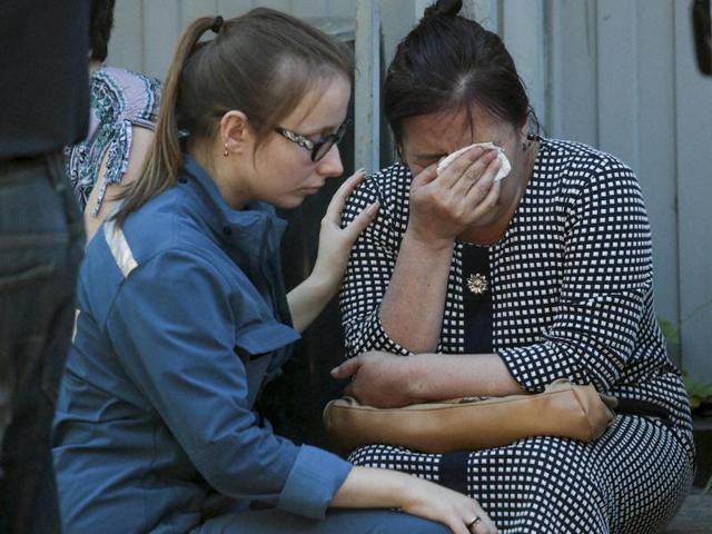A Russian Emergency Situation employee, left, comforts a woman as colleagues and relatives of dead workers from Kyrgyzstan gather next to the burnt building of a printing plant's warehouse in Moscow, Russia, Saturday, Aug. 27, 2016.(AP)