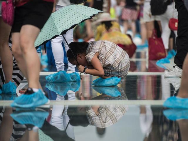 A girl looks through the glass on the bridge. To ensure that the thrilling experience is safe, the authorities  organised a string of media events, including one where people were encouraged to try and smash the bridge’s glass panels with a sledge hammer, and another where they drove a car across it. (AFP) 