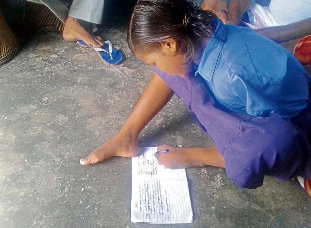 Kirti writes her homework with foot after returning from school. She lost her hands in an accident four years ago. (HT Photo) Kirti writes her homework with foot after returning from school. She lost her hands in an accident four years ago. (HT Photo)