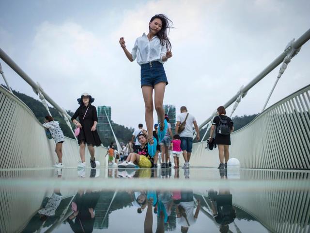 A visitor jumps for a photograph on the glass-bottomed bridge. No stilettos are allowed here. (AFP) 