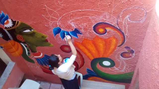 A student of Kamala Nehru College paints tribal art on a wall inside the college.