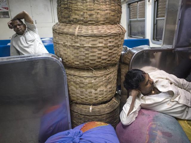 A fisherman’s empty baskets block the entryway while he rests in front of them inside the first local train from Karjat to Mumbai on Saturday. (Pratik Chorge/HT ) 