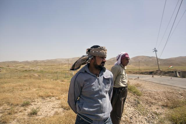 In this May 19, 2016 photo, Arkan Qassim, center, stands at the site where he witnessed the killing dozens of Yazidi men including two sons of Rasho Qassim, right, in August 2014 in Hardan, northern Iraq. Both survivors say they simply want the graves exhumed. (AP) In this May 19, 2016 photo, Arkan Qassim, center, stands at the site where he witnessed the killing dozens of Yazidi men including two sons of Rasho Qassim, right, in August 2014 in Hardan, northern Iraq. Both survivors say they simply want the graves exhumed. (AP)
