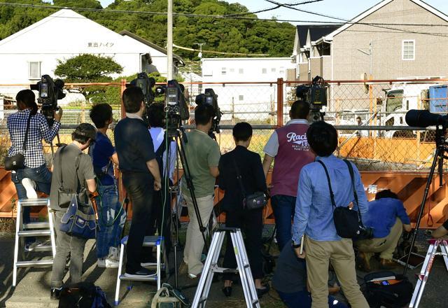 Journalists look at an apartment, center back, where Yasuhide Mizobata, a murder suspect, with guns holes up in a standoff. (AP) Journalists look at an apartment, center back, where Yasuhide Mizobata, a murder suspect, with guns holes up in a standoff. (AP)