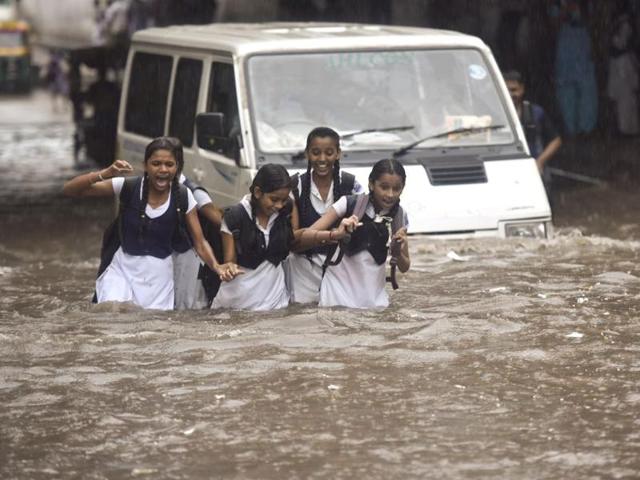 School students wade through a waterlogged road in New Delhi on Wednesday.(Raj K Raj/HT PHOTO)