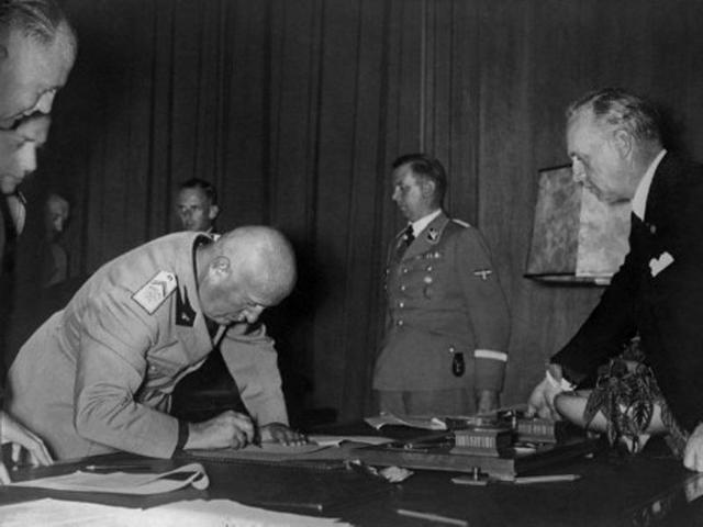 Italian head of government Benito Mussolini is photographed signing the Munich Treaty as Hitler's secretary Martin Bormann (2nd right) and Nazi foreign minister Joachim von Ribbentrop (right) look on, on September 29, 1938 in Munich. The Munich Treaty signed between Nazi Germany, France, Italy and the United Kingdom authorised Hitler to annex a Czech territory called the Sudetes. Germany finally invaded Czechoslovakia on March 15, 1939. (AFP Archive)