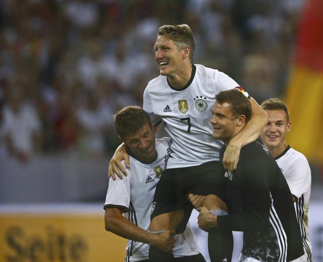 Germany's Thomas Mueller (left) and Manuel Neuer (right) pick up Bastian Schweinsteiger on their shoulders after the match. (Reuters Photo)