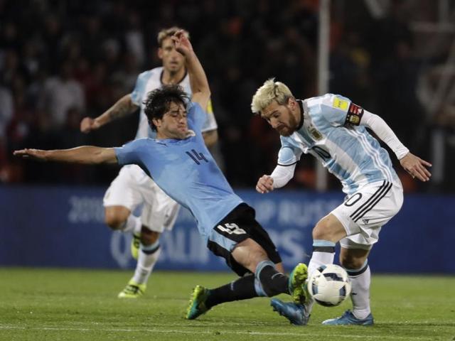 Argentina's Lionel Messi, right, fights for the ball with Uruguay's Nicolas Lodeiro. (AP Photo)