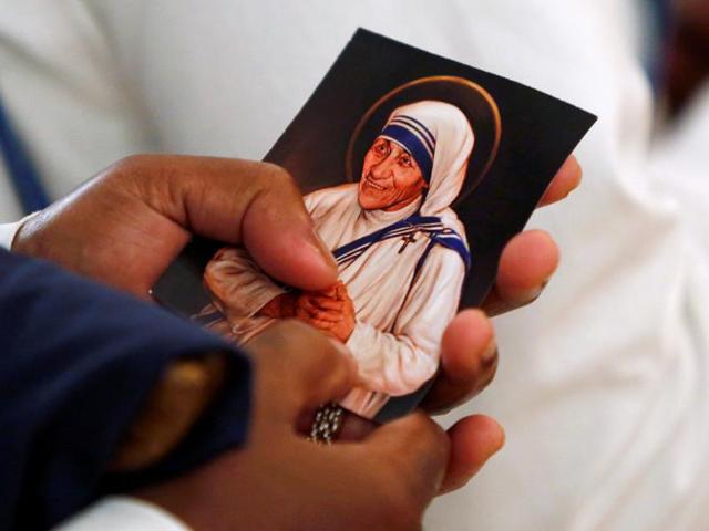 A candle, adorned by an image of Mother Teresa, burns as a woman pays her respects during a ceremony marking Mother Teresa's death anniversary in Kolkata September 5, 2011(REUTERS)