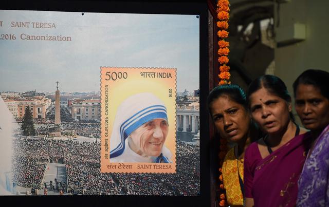 Indian bystanders pose for a picture near a board displaying a commemorative postage stamp of Mother Teresa during its release function in Mumbai. (AFP) Indian bystanders pose for a picture near a board displaying a commemorative postage stamp of Mother Teresa during its release function in Mumbai. (AFP)