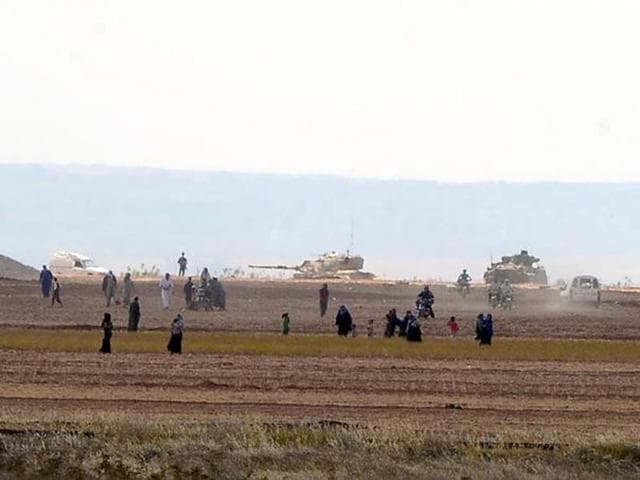 Syrian civilians, with Turkish Army tanks in the background, walk through the Turkish border as they are pictured from a village in Kilis province. (Reuters) Syrian civilians, with Turkish Army tanks in the background, walk through the Turkish border as they are pictured from a village in Kilis province. (Reuters)