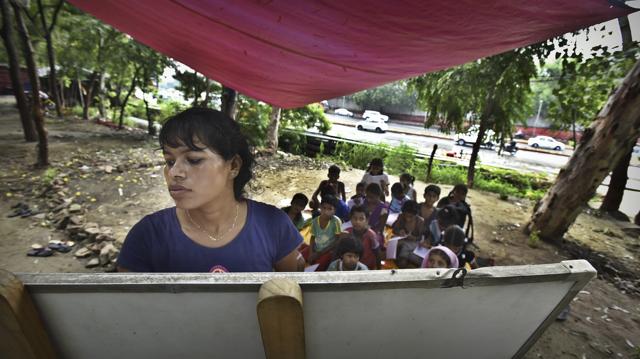 Neetu Singh teaches about 30 students every afternoon at her impromptu school on a sidewalk near Pragati Maidan’s gate number 1, adjacent to the Shiv Hanuman Panchvati Mandir. (Raj K Raj/HT PHOTO)
