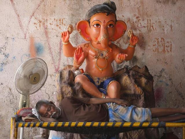 A man sleeps as he waits for customers to sell an idol of Lord Ganesha during Ganesh Chaturthi festival in Ahmadabad. All idols that have been worshipped will be immersed in water bodies after at the end of the festival.  (Ajit Solanki/AP) 