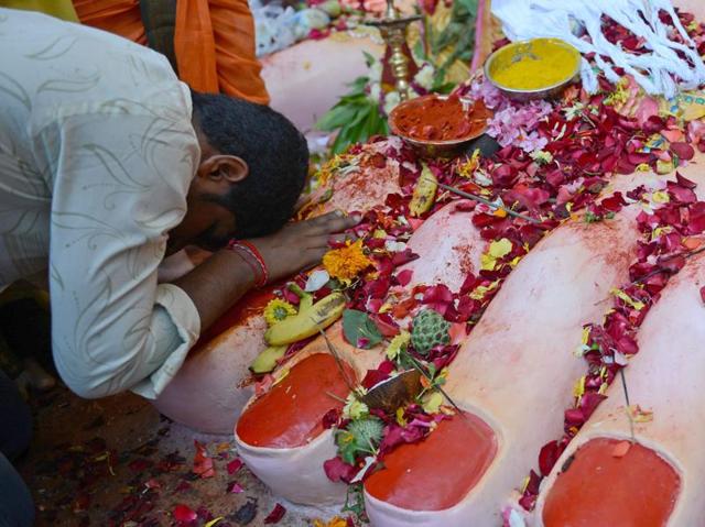 A devotee offer prayers at the foot of a 17- metre tall idol of Lord Ganesha in Hyderabad. Devotees bring home idols of Lord Ganesha in order to invoke his blessings for wisdom and prosperity, during the eleven-day long festival which culminates with the immersion of the idols in water bodies. (NOAH SEELAM/AFP) 
