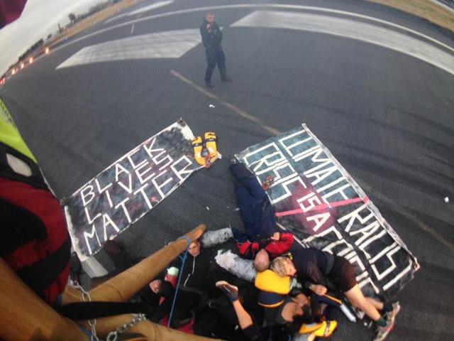 Emergency services surround protestors from the movement Black Lives Matter after they locked themselves to a tripod on the runway at London City Airport in London. (AFP) Emergency services surround protestors from the movement Black Lives Matter after they locked themselves to a tripod on the runway at London City Airport in London. (AFP)