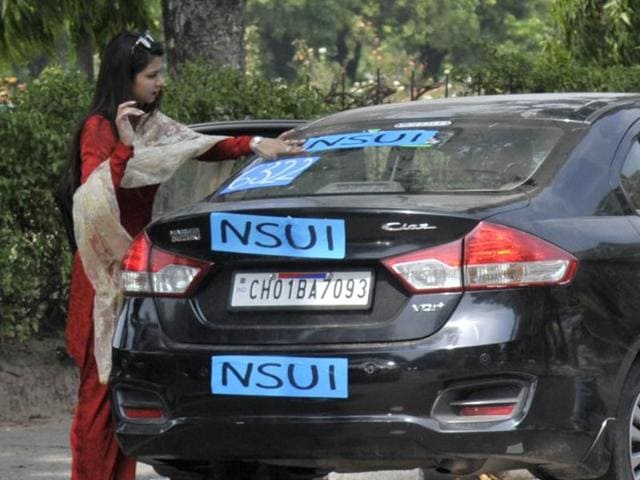 A girl pastes stickers of the NSUI on her car on the Panjab University campus on the eve of student union elections, in Chandigarh on Tuesday. (Ravi Kumar/HT Photo)