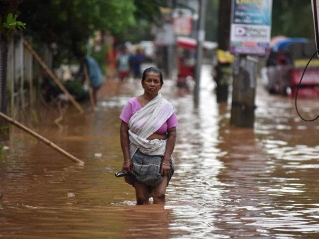 An Indian woman wades through knee-deep floodwaters in the Anilnagar area of Guwahati.(AFP File Photo)